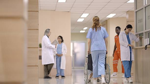 istock In the busy hospital lobby, doctors and nurses move quickly between patients, while a young girl holding her mother’s hand waits to be called into the examination room for a medical check-up. The setting reflects dedication and healthcare in action. 2230362962