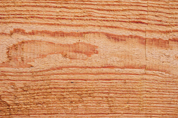 istock Close up showing the texture of a solid piece of reddish wood with prominent grain patterns, knots and a natural rough surface 2230367348