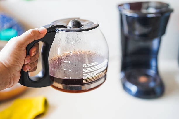 Hand holding coffee pot with freshly brewed coffee