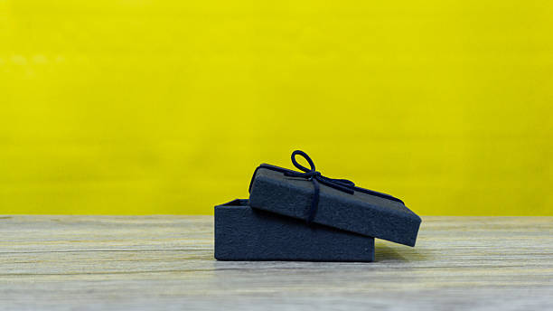 istock Open black gift box displayed on wooden table with vibrant yellow background, great for festive, celebration, or product display imagery. 2230368672