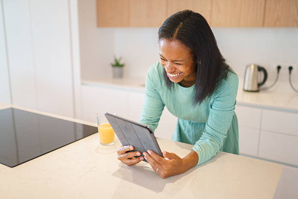 istock Mid Adult Multiracial Female Laughing While Using Tablet in Kitchen 2230375491