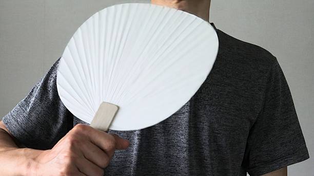 Close-up of a person fanning themselves with a fan