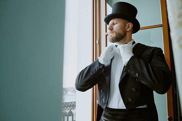 istock Caucasian Young Adult Man Adjusting Bow Tie While Standing near Window 2230384098