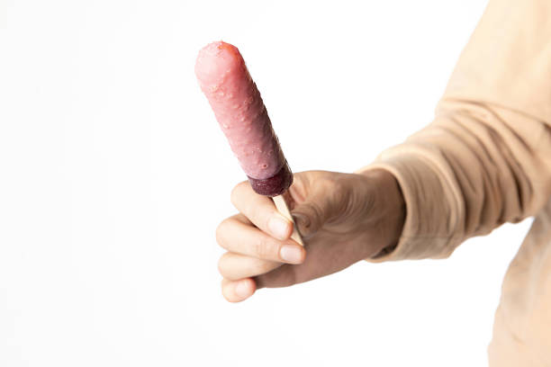 Minimalist food photo of hand holding popsicle ice cream on white background.