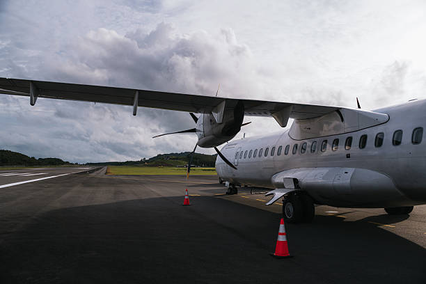 Turboprop airplane standing still on the runway of a small airport under a cloudy sky, ready for passengers to board