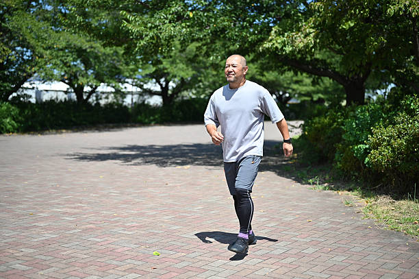 A 50-year-old man runs for health on a sunny summer day.