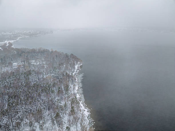 istock November landscape with covered with first snow birch and spruce forest on lake shore. First snow on lake. 2230398417
