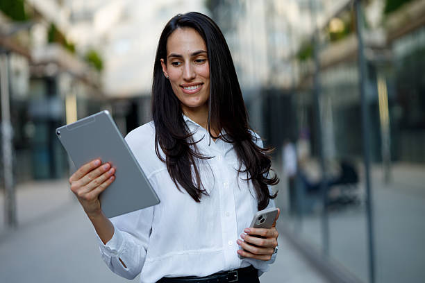 istock Professional woman working remotely, navigating urban landscape with digital devices 2230405199
