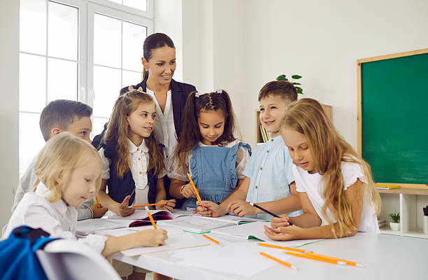 istock Group of elementary school children and teacher write and draw pictures in class 2230405843