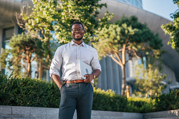 istock Smiling businessman holding laptop in urban setting 2230407108