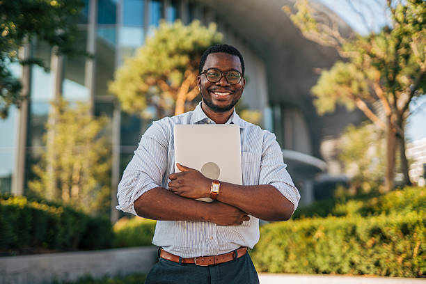 istock Smiling businessman holding laptop in urban setting 2230407329