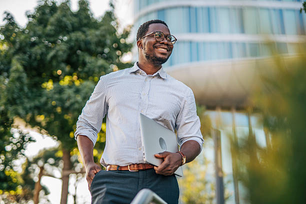 Smiling businessman walking outside holding laptop