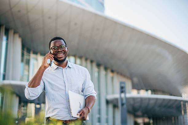 istock Smiling businessman walking and talking on phone outside office 2230408038