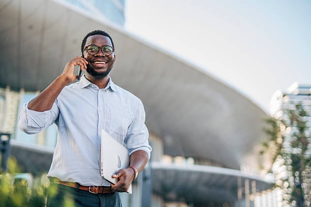istock Smiling businessman walking and talking on phone outside office 2230408041