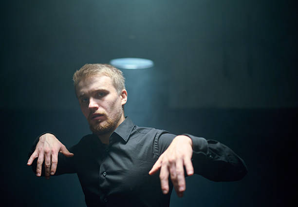 A man is raising his hands and looking up towards the sky with a pleading expression