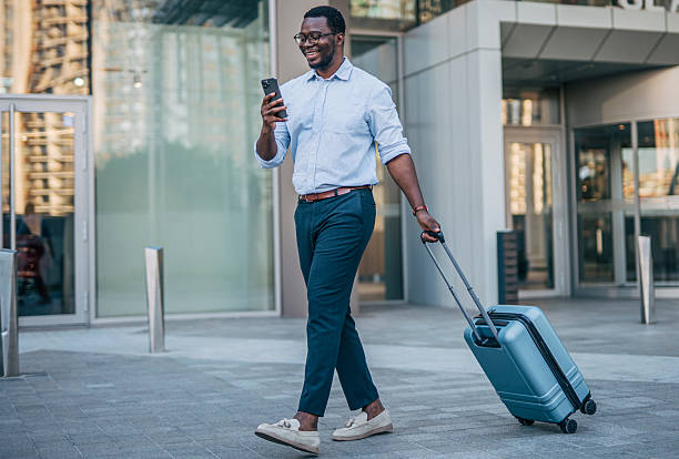 istock Businessman walking with suitcase and using smartphone 2230408411