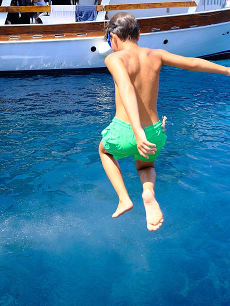 9 year old boy jumping to the sea from boat, turquoise colored water