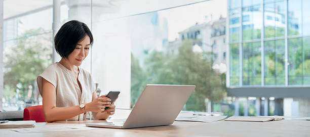 istock Young eastern successful business woman manager ceo using cell phone mobile. Smiling asian mature female businesswoman holding smartphone in office for trading working call online. Banner, copy space 2230412911