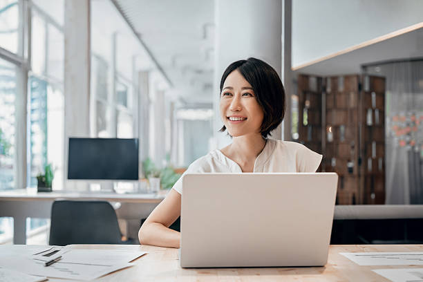 istock Professional female executive entrepreneur in suit working on computer pc at company workplace, looking dreaming. Asian smiling middle aged business woman using laptop at work in office. Copy space 2230412938