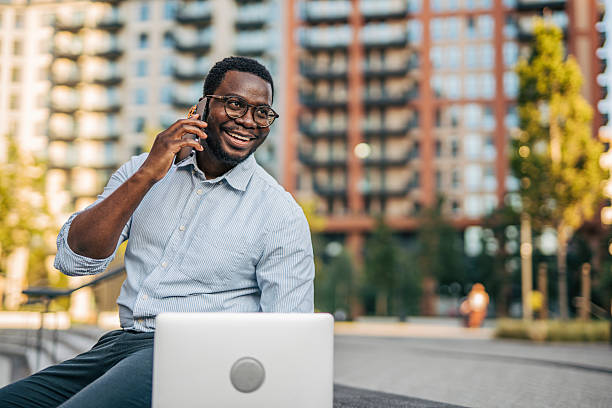 istock Young businessman working outdoors with laptop and talking on smartphone 2230416880