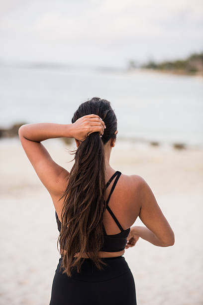 istock Woman facing ocean tying ponytail 2230419055