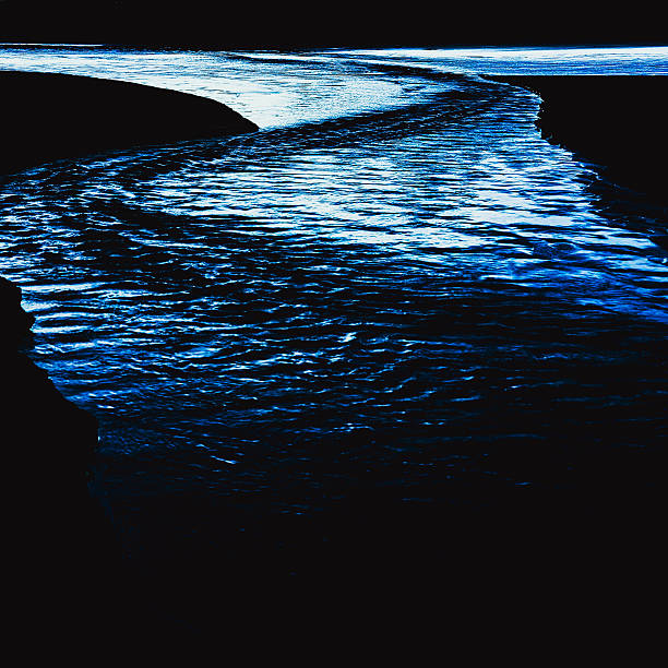 Artistic abstract texture of rippling water in deep blue tones. The image highlights fluid patterns, light reflections and strong contrasts, creating a dramatic and modern background. Perfect for use in graphic design, digital art, and contemporary visual projects.
