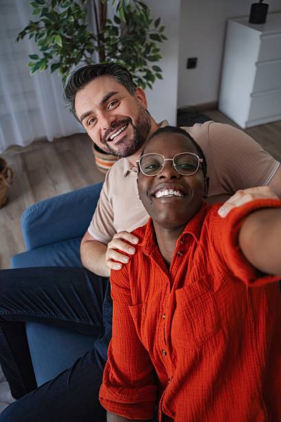 istock Happy multi-ethnic couple taking a selfie on the sofa at home 2230421661