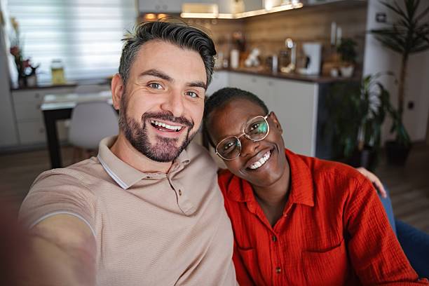 istock Happy multi-ethnic couple taking a selfie at home smiling at the camera 2230421874