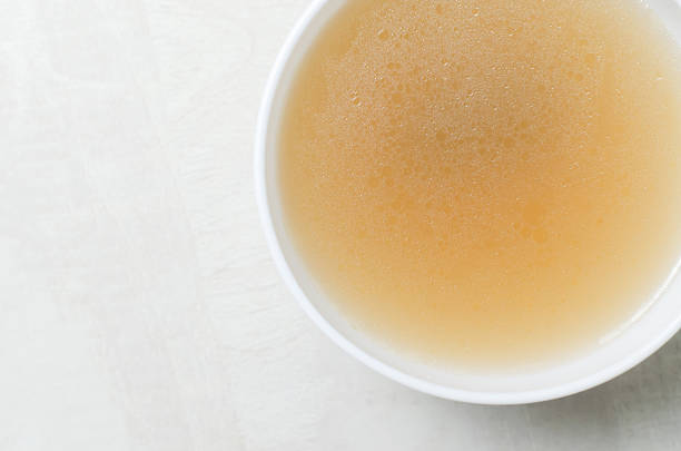 Veal bone broth in a white bowl on a white table. Collagen concept. Selective focus. Horizontal orientation. Copy space. Top view