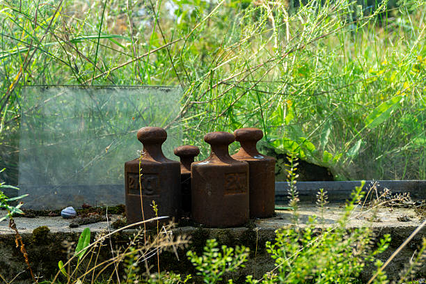 istock Old cast iron weight scales placed on a concrete base surrounded by grass and weeds, symbolizing traditional weighing methods in a rustic natural outdoor environment. 2230423031