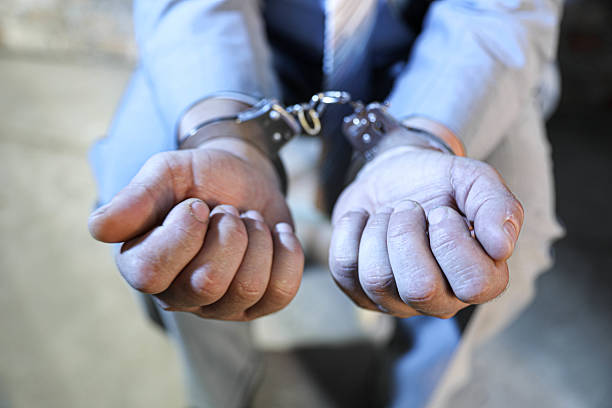 Close-Up Of Senior Businessman’s Hands In Handcuffs, Wearing Gray Suit And White Shirt, Symbolizing Crime Scene, Captivity, And Restriction.