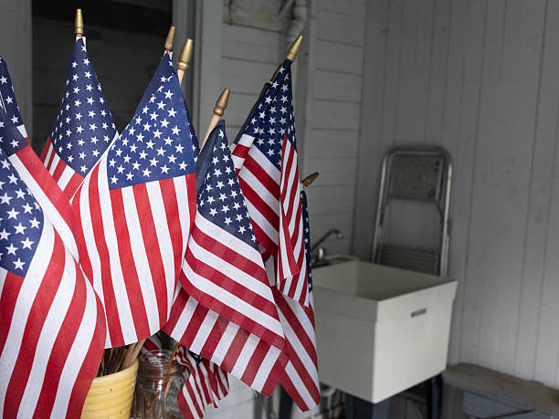 Red, white and blue American flags are stored in a flowerpot on a gardening bench when not in use as decorative elements for holiday display. The flags can be stuck into the ground or placed in a holder at any time but are most appropriate to celebrate Memorial Day, Fourth of July or Independence Day, Labor Day and Flag Day.