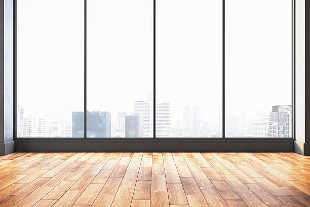 istock Modern empty room with wooden floor and large panoramic windows overlooking a bright cityscape skyline in daylight. 3D Rendering. 3D Rendering 2230432219