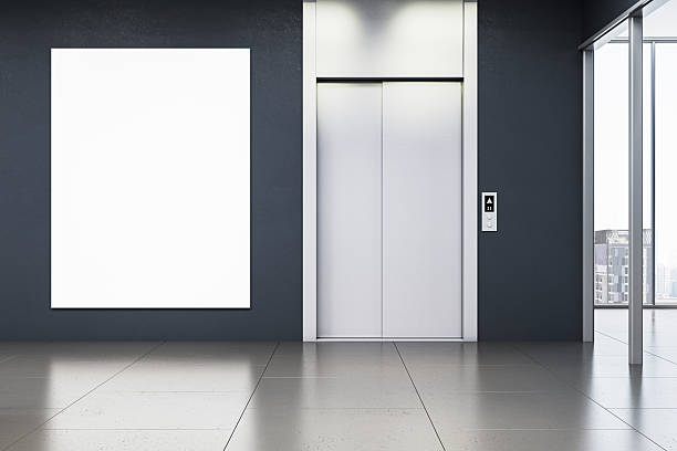 istock Vertical blank poster mockup on dark wall next to closed elevator doors in modern office or hotel hallway interior with city view window. 3D Rendering 2230432232