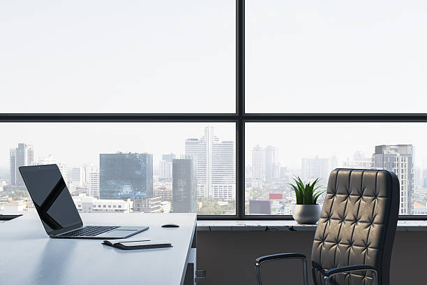 istock Modern office interior with laptop on desk and panoramic city view through large windows in high-rise building workspace concept. 3D Rendering 2230432343