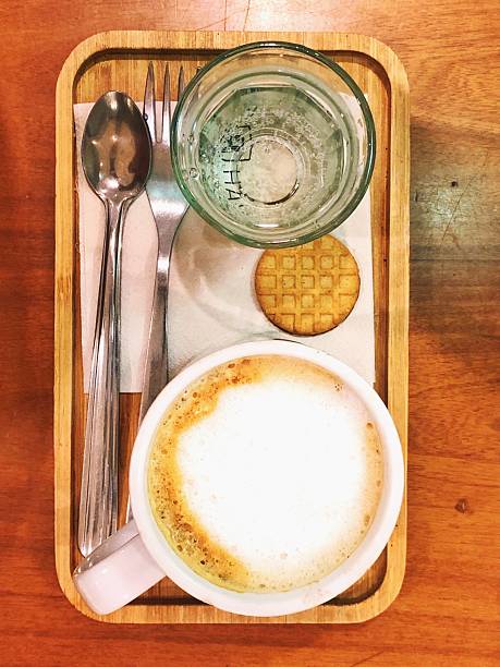 Top view of a latte, water glass, and cookie on a wooden tray