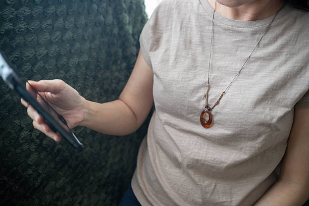 Relaxed and focused, she uses her smartphone while unwinding on the sofa in her cozy living space.