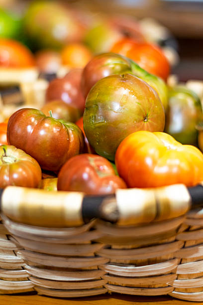 Ripe red tomatoes are neatly arranged in wicker baskets, ready for sale at a local farmers market