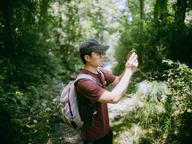 istock Young Asian man using his smartphone while hiking in the forest 2230442109