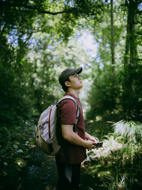 istock Young Asian man hiking in the forest 2230442111