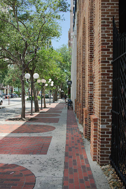 istock Brick Sidewalk Lined with Lush Trees and Vintage Street Lamps 2230446621