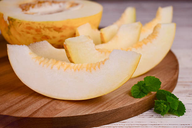 istock Sweet melon cut into pieces on white wooden background. 2230447083