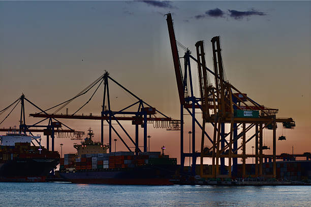 istock Cargo ship docked at port during colorful sunset sky 2230449314