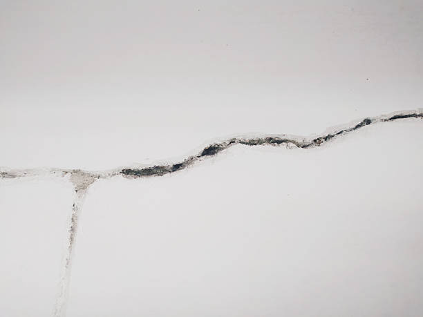 Cracked wall detail with a fissure running across a plain white surface. Metaphor for vulnerability, imperfection, or structural damage. Useful for construction or repair themes.