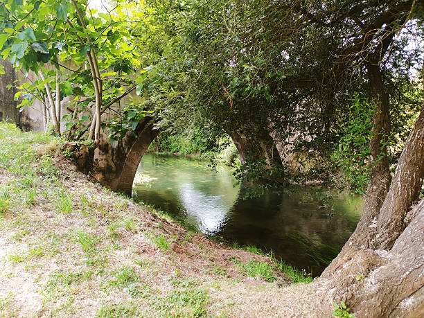 istock Serene river flowing under an old stone bridge, framed by lush greenery and trees. Evokes tranquility, nature, and history. Ideal for travel, environment, and landscape themes. 2230449472