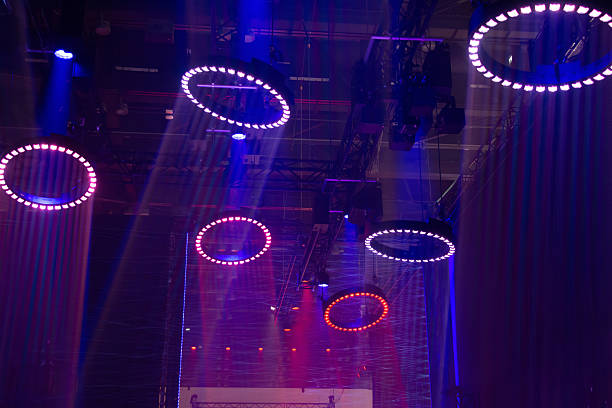 The illuminated by vivid blue and purple lights, with circular light patterns projected onto the floor, creating a dynamic and immersive visual environment. The lighting setup suggests a high-tech, futuristic aesthetic, often used in concerts, electronic dance events, or multimedia art installations.