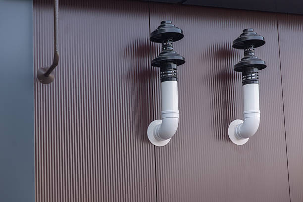 Two white ventilation pipes with black caps protruding from a corrugated metal wall