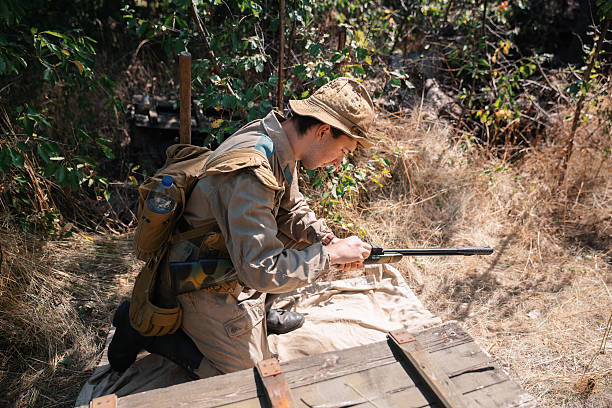 World war II soldier is preparing his rifle during a reenactment in a forest