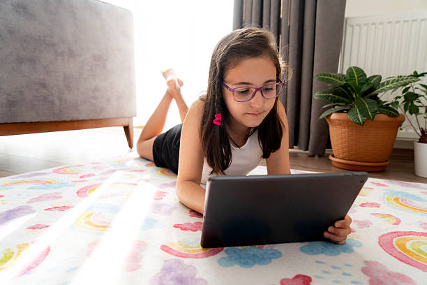 istock Little girl using a digital tablet while lying on the floor at home 2230457096