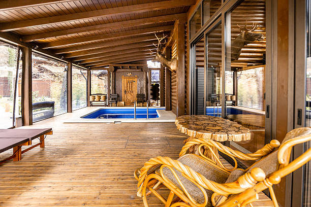 A wooden deck with a pool and a table with a chair. The deck is surrounded by a wooden fence and has a view of the pool